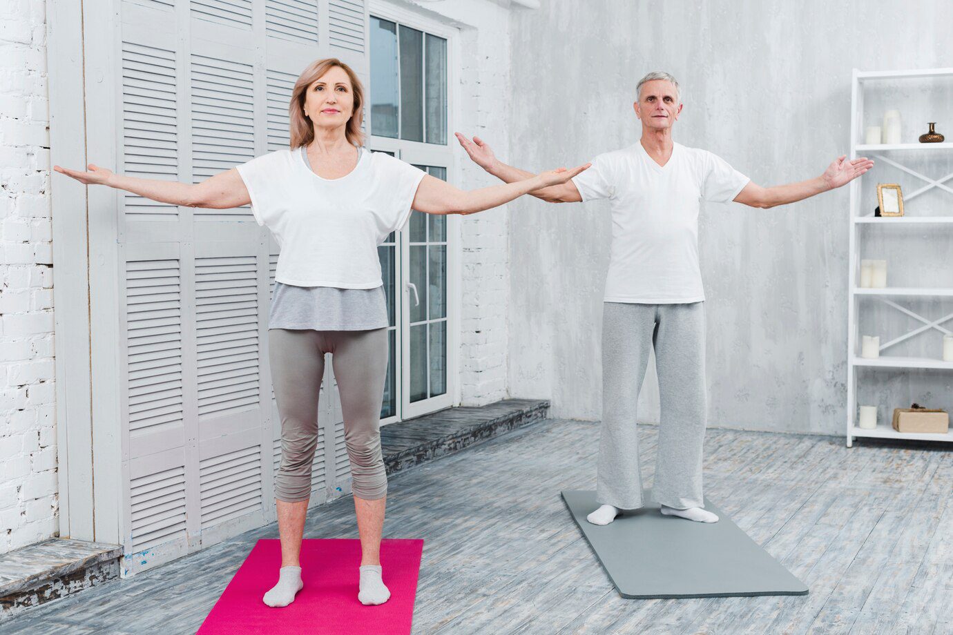 A man and woman standing on yoga mats.