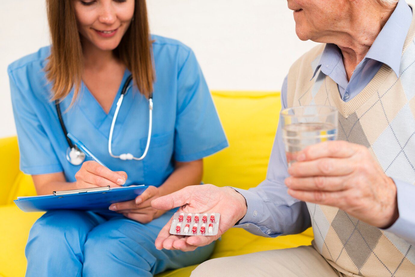 A nurse is holding pills and talking to an older man.