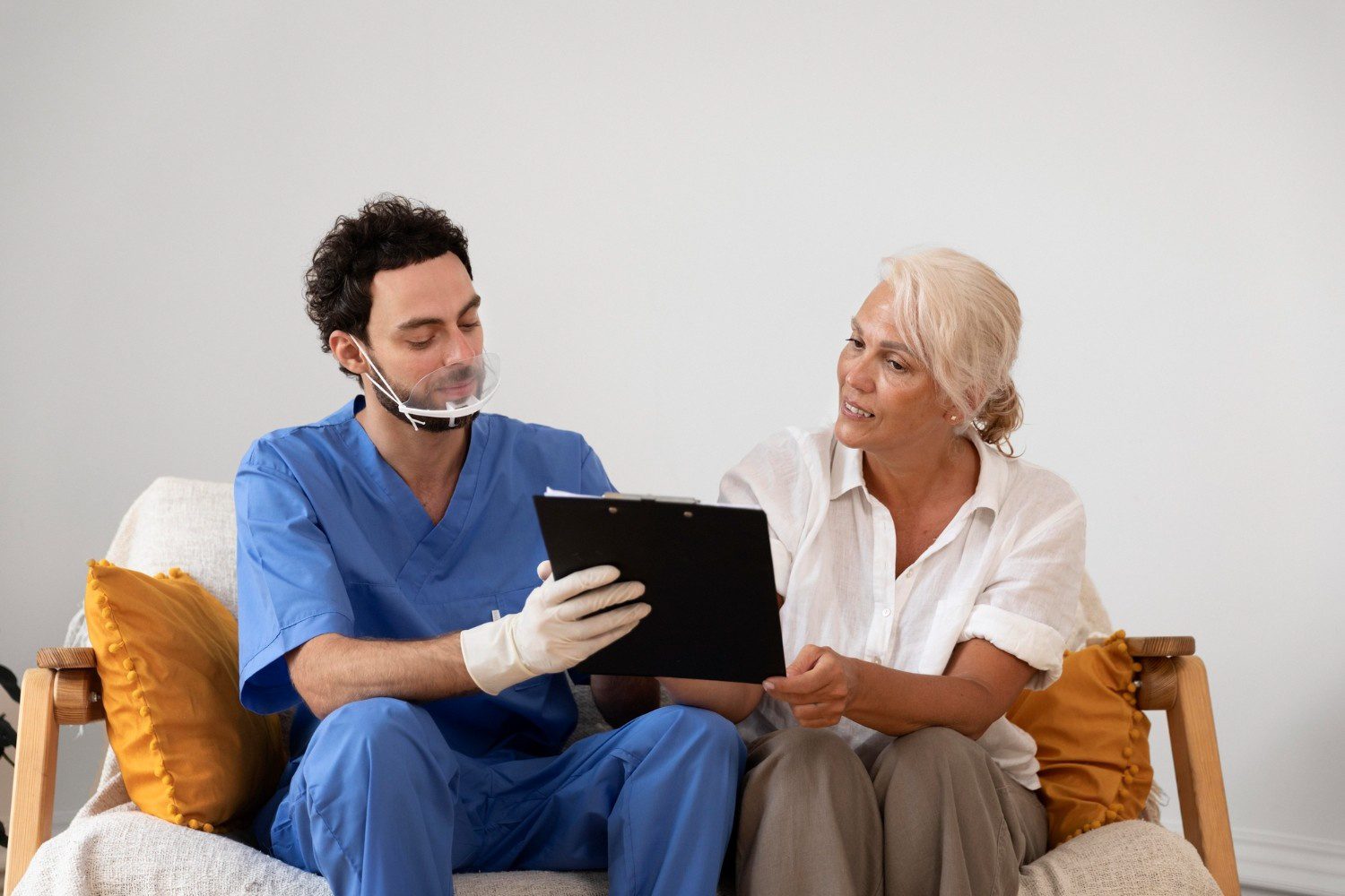 A man and woman sitting on the couch looking at an ipad.