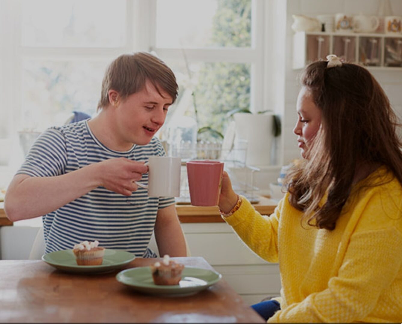 A man and woman sitting at a table with cups.