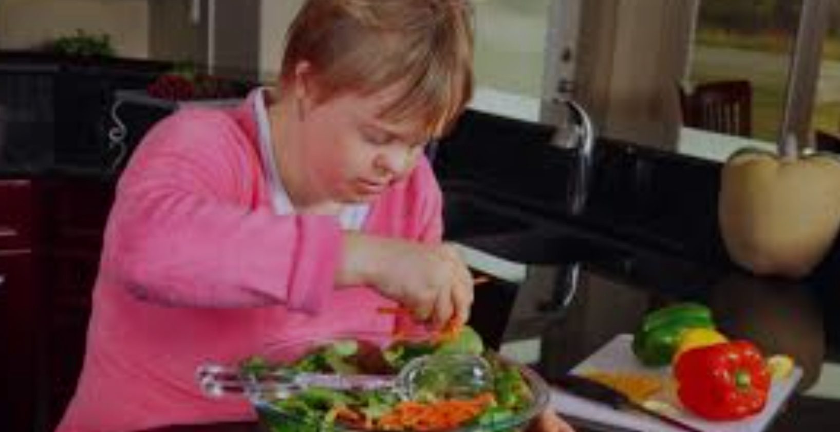 A child is eating salad in the kitchen.